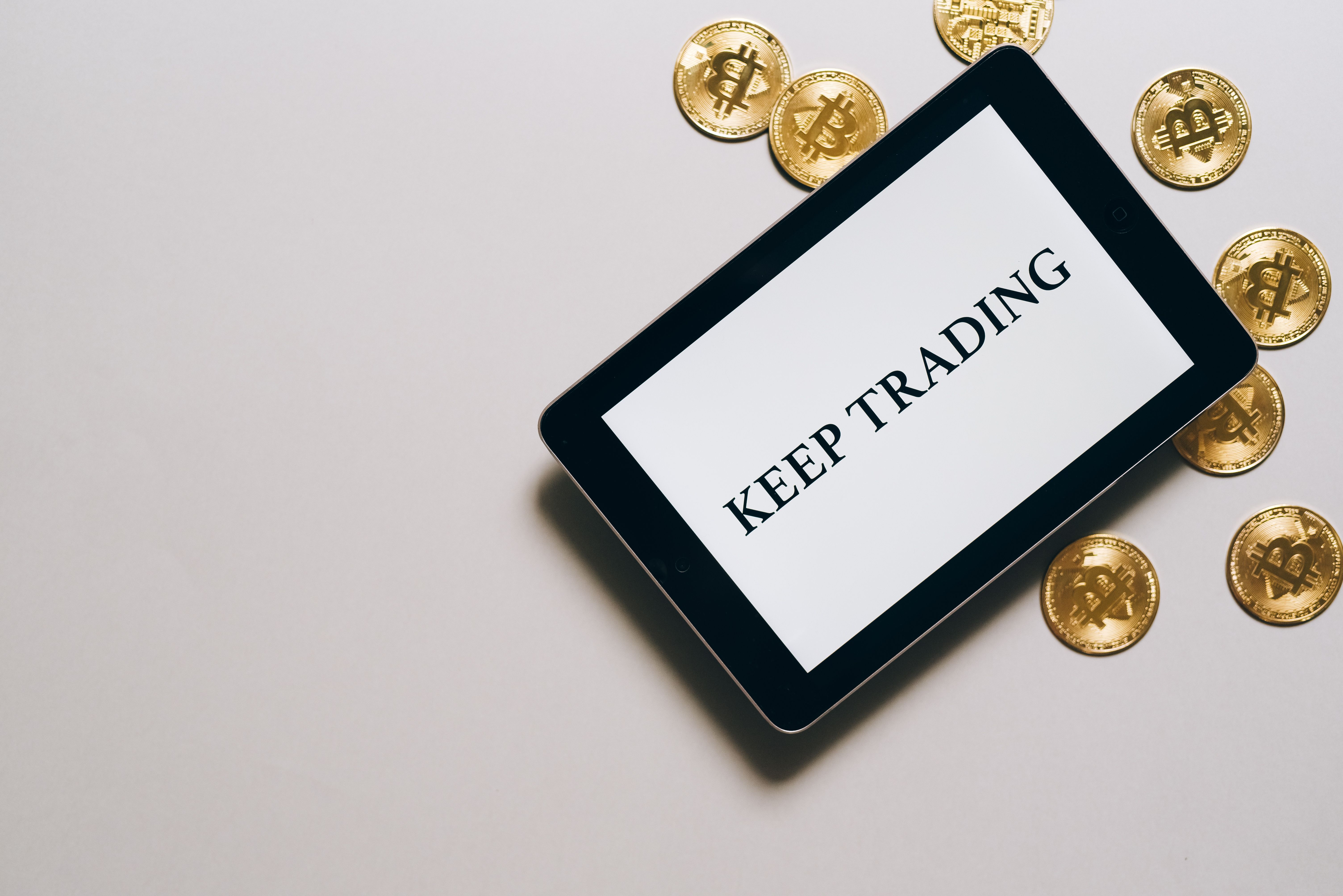 แท็บเล็ตแสดงข้อความ Keep Trading พร้อมเหรียญสกุลดิจทัล สื่อถึงความสม่ำเสมในการเทรด